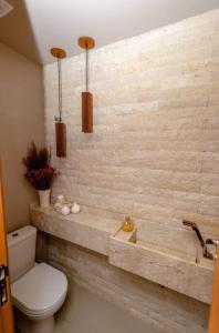 a bathroom with a toilet and a stone wall at Casa 19 da Vila Beija Flor in Mucugê
