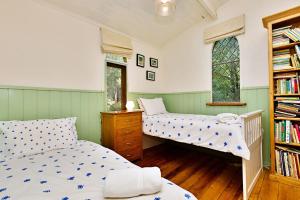 a bedroom with two beds and a book shelf at Blue Gum Church - Artistic Retreat in Beechworth