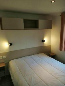 łóżko w sypialni z dwoma światłami na ścianie w obiekcie Bungalow de 2 chambres avec piscine partagee et terrasse a Condrieu w mieście Condrieu