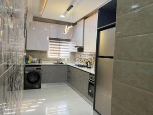 uma cozinha com armários brancos e uma máquina de lavar e secar roupa em Gorgeous 2 Bedroom with parking inside Banana Island, Ikoyi em Lagos