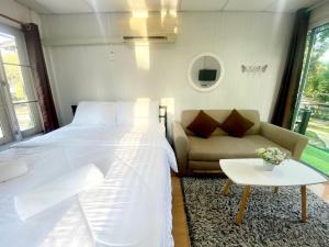 a bedroom with a bed and a couch and a table at Sleep Home Khaoyai in Pak Chong