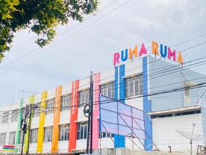 un edificio con coloridos signos a su lado en Ruma Ruma Hotel Kenten - Palembang, en Sukarami