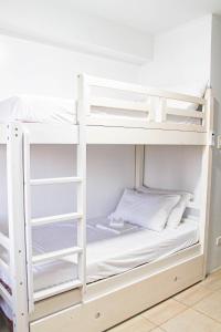 a bunk bed with white bunk beds in a room at Titan Condo at Studio City Tower 3 Alabang in Manila