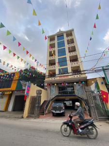 a man riding a motorcycle in front of a building with flags at Kim Thoa Hotel Trung Khanh in Bản Piên