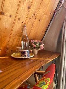 una botella en una mesa de madera con un plato en Nhà của Nếp en Plei Brel (2)