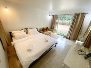 a bedroom with a large white bed with a window at Sleep Home Khaoyai in Pak Chong