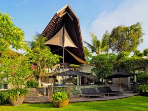 a building with chairs and umbrellas in a yard at Villa Toraja by LifestyleRetreats in Canggu