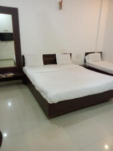 1 dormitorio con 1 cama con sábanas y almohadas blancas en Sai Amaravathi Residency, en Shirdi