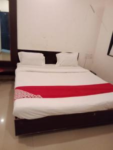 Una cama blanca con una manta roja. en Sai Amaravathi Residency, en Shirdi