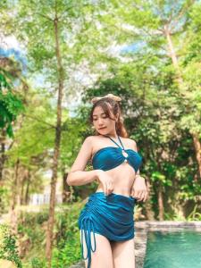 Una mujer con un vestido azul parada junto a una piscina en Bách Thanh Villa C15 - FLAMINGO ĐẠI LẢI, en Phúc Yên