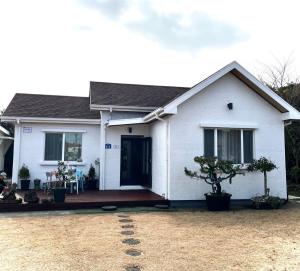 uma casa branca com um alpendre frontal em Sehwa Stay em Jeju