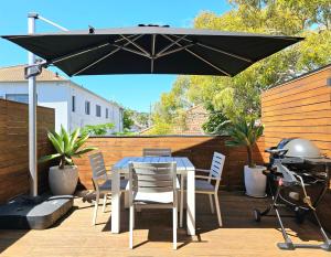una mesa y sillas bajo una sombrilla en un patio en The Mitchell Bondi Sun Terrace 2 en Sídney