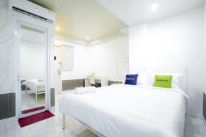 a white bedroom with a large bed and a desk at Urbanview Hotel Kota Tua Jakarta in Jakarta