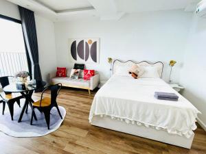 um quarto com uma cama branca, uma mesa e cadeiras em Vinhomes Dcapitale - Studio em Hanói