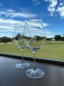 due bicchieri da vino seduti su un tavolo di fronte a una finestra di The Victoria Golf Club a Melbourne