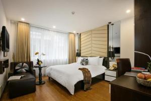 a bedroom with a large white bed and a chair at Splendid Holiday Hotel Spa in Hanoi