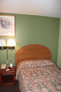 1 dormitorio con 1 cama, 2 lámparas y teléfono en Oak Hill Inn and Suites, en Tahlequah