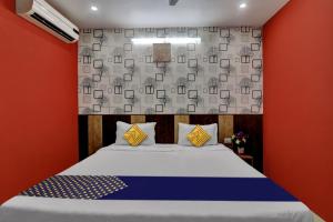 um quarto com uma cama e uma parede vermelha em SPOT ON Hotel C S Tower em Lucknow