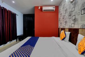 ein Schlafzimmer mit einem Bett und einer roten Wand in der Unterkunft SPOT ON Hotel C S Tower in Lucknow