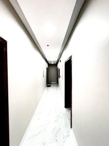 um corredor de um edifício com paredes brancas e uma porta preta em Brand new apartment em Al Fayşalīyah