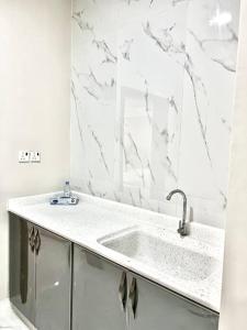 uma casa de banho branca com um lavatório e paredes em mármore em Brand new apartment em Al Fayşalīyah