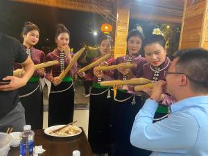 Un uomo che scatta una foto a un gruppo di donne che tengono dei bastoni di Nậm Thia Homestay a Yên Bái
