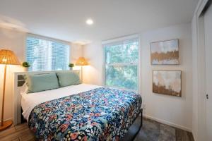 a bedroom with a bed with a floral bedspread and two windows at Coastal Tiny House 2 Queen Beds low loft in San Luis Obispo