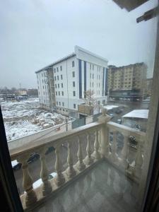 a view of a snowy city from a balcony at Уютная квартира in Tashkent