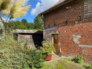 un bâtiment en briques avec une porte et quelques plantes dans l'établissement Appartement tout équipé dans un cadre naturel, proche du Parc Avesnois et commodités, jusqu'à 5 pers. - FR-1-510-189, à Orsinval