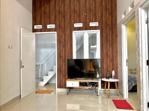 un salon avec une télévision sur un mur en bois dans l'établissement Harmoni Guest House 2 Bedroom - Near Kasongan, à Jarakan