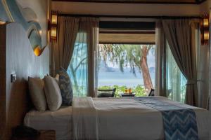 una camera con un letto e una grande finestra di Tup Kaek Sunset Beach Resort-SHA Plus a Tab Kaek Beach