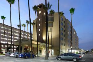 un edificio con auto parcheggiate in un parcheggio con palme di Courtyard by Marriott Los Angeles LAX / Century Boulevard a Los Angeles