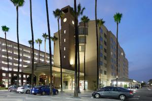 un edificio con coches aparcados en un aparcamiento con palmeras en Courtyard by Marriott Los Angeles LAX / Century Boulevard, en Los Ángeles