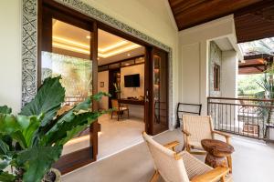 a room with a balcony with chairs and a television at Svarga Bebek Villas in Ubud