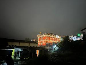 un edificio con luces encendidas en una ciudad por la noche en Coorg Cu’s Homestay, en Madikeri