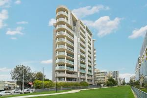 a tall white apartment building with a green lawn at KOZYGURU MASCOT 2 BED Apt FREE PARKING NMA103 in Sydney