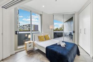 a bedroom with a bed and a large window at KOZYGURU MASCOT 2 BED Apt FREE PARKING NMA103 in Sydney