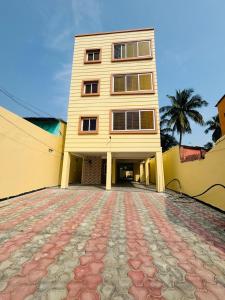 un grand bâtiment jaune avec un palmier derrière lui dans l'établissement Hotel Golden Homes Inn Puri, à Purî