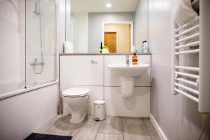 La salle de bains blanche est pourvue de toilettes et d'un lavabo. dans l'établissement Leeds Vibrant 2 Bedroom Sleeps 4, à Leeds