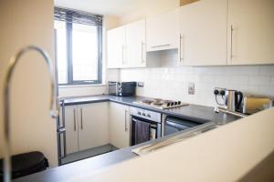 a kitchen with white cabinets and a sink at Leeds Vibrant 2 Bedroom Sleeps 4 in Leeds