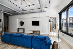 a living room with a blue couch and a large window at Art District Loft - 4BD/2BA Downtown SGF in Springfield