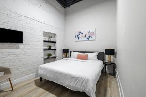 a white bedroom with a bed and a white brick wall at Art District Loft - 4BD/2BA Downtown SGF in Springfield
