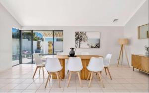 a dining room with a table and white chairs at Beachfront Bliss - Private Pool and Beach Access in Mandurah