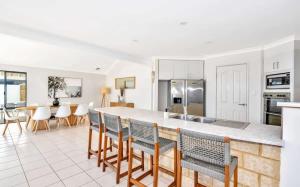 a kitchen with a bar with chairs and a counter top at Beachfront Bliss - Private Pool and Beach Access in Mandurah +38 photos