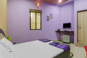 KāyankulamにあるOYO HOTEL RAGAの紫の壁のベッドルーム(ベッド1台、テレビ付)