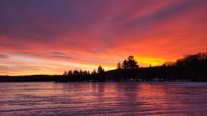 einen Sonnenuntergang über einem See mit rotem und orangefarbenem Himmel in der Unterkunft Bonnie View Inn in Haliburton