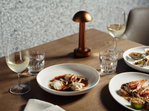 a wooden table with plates of food and glasses of wine at Ardo in Townsville