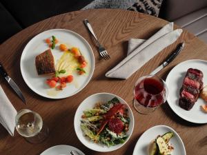 a wooden table with plates of food and a glass of wine at Ardo in Townsville