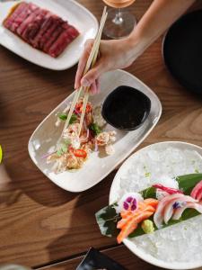 a table with plates of food and a person holding chopsticks at Ardo in Townsville