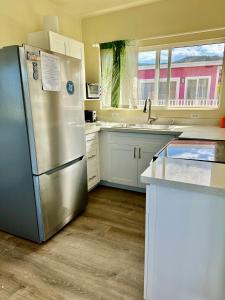 eine Küche mit einem Kühlschrank aus Edelstahl und weißen Schränken in der Unterkunft Mokulē'ia Beach Houses at Owen's Retreat in Waialua